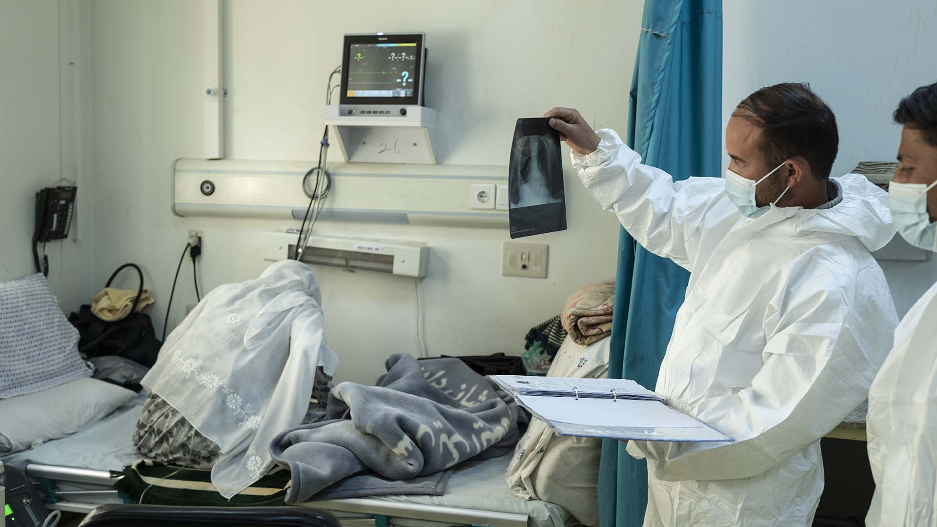 Le personnel de l'hôpital Afghan-Japon examine une radiographie pulmonaire dans la section des urgences COVID-19 à côté d'un patient à Kaboul, Afghanistan, le jeudi 9 décembre 2021. (AP Photo/ Petros Giannakouris)