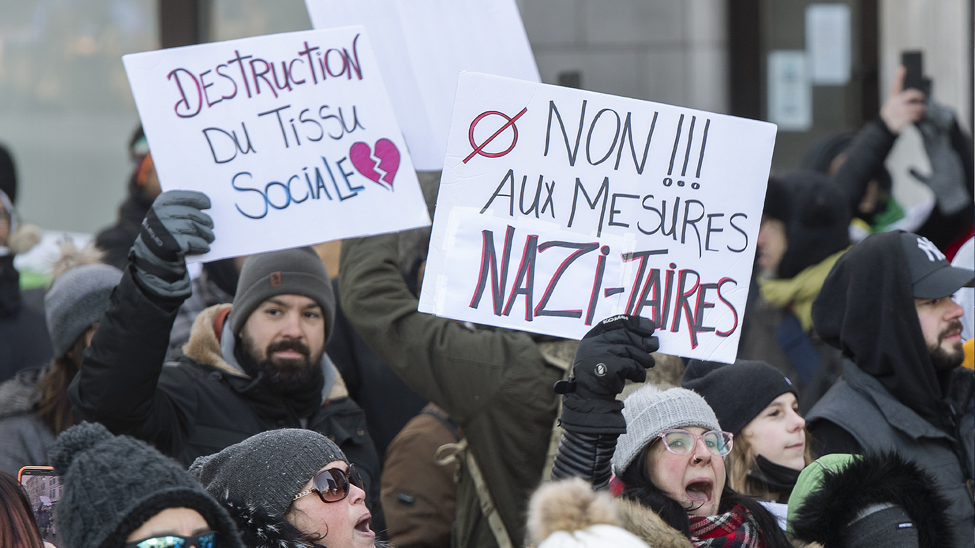 Des manifestants réunis à Montréal affichent des pancartes avec des slogans contre les mesures sanitaires.
