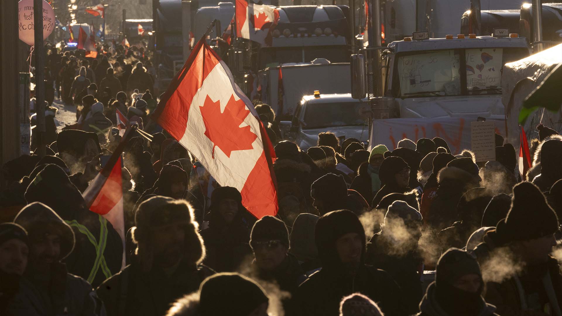 Des manifestants marchent autour de camions stationnés au centre-ville pour protester contre les restrictions liées à la COVID-19, à Ottawa, le samedi 5 février 2022.