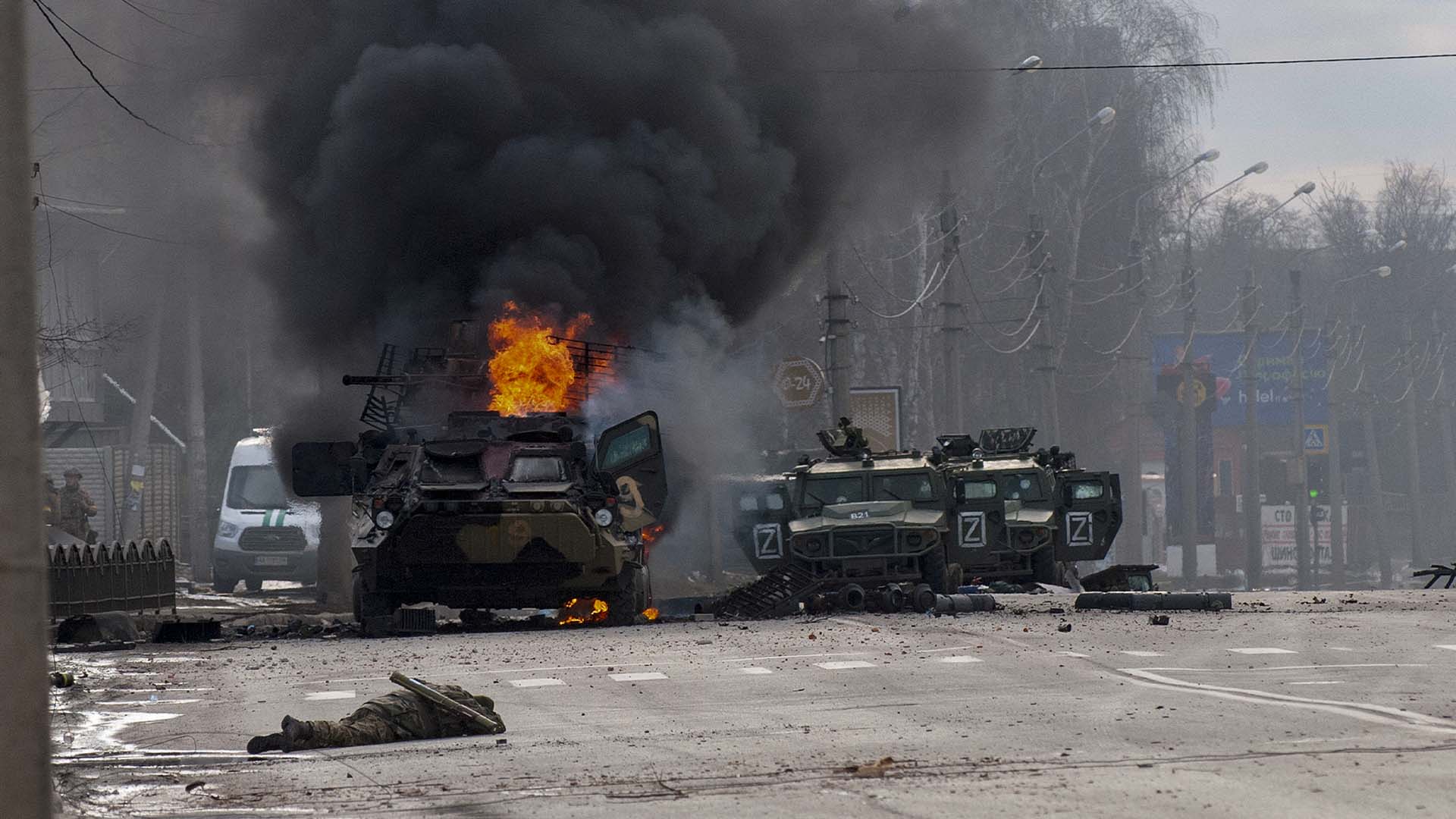 Un véhicule blindé de transport de troupes brûle et des véhicules utilitaires légers endommagés sont abandonnés après des combats à Kharkiv, en Ukraine, le dimanche 27 février 2022.