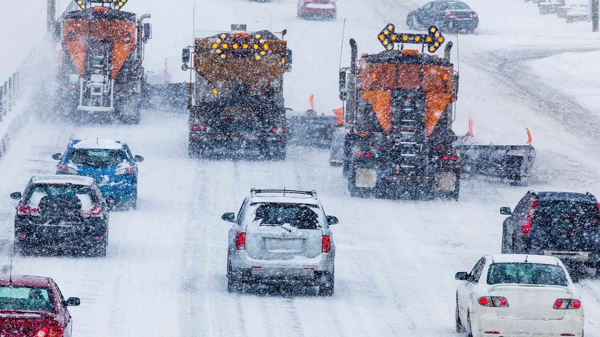 Des camions déneigent une portion de route en hiver.
