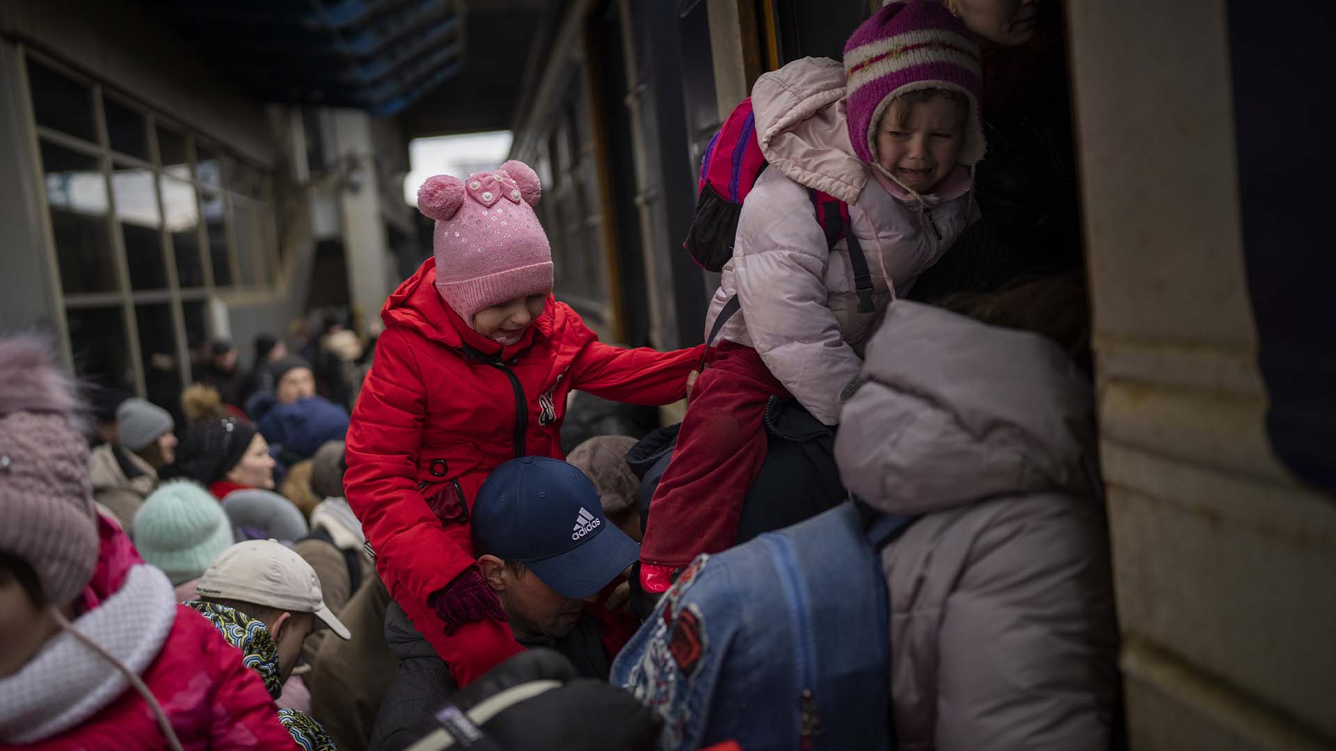 Des personnes tenant leurs enfants ont du mal à monter dans un train pour Lviv à la gare de Kiev, en Ukraine, le lundi 7 mars 2022.