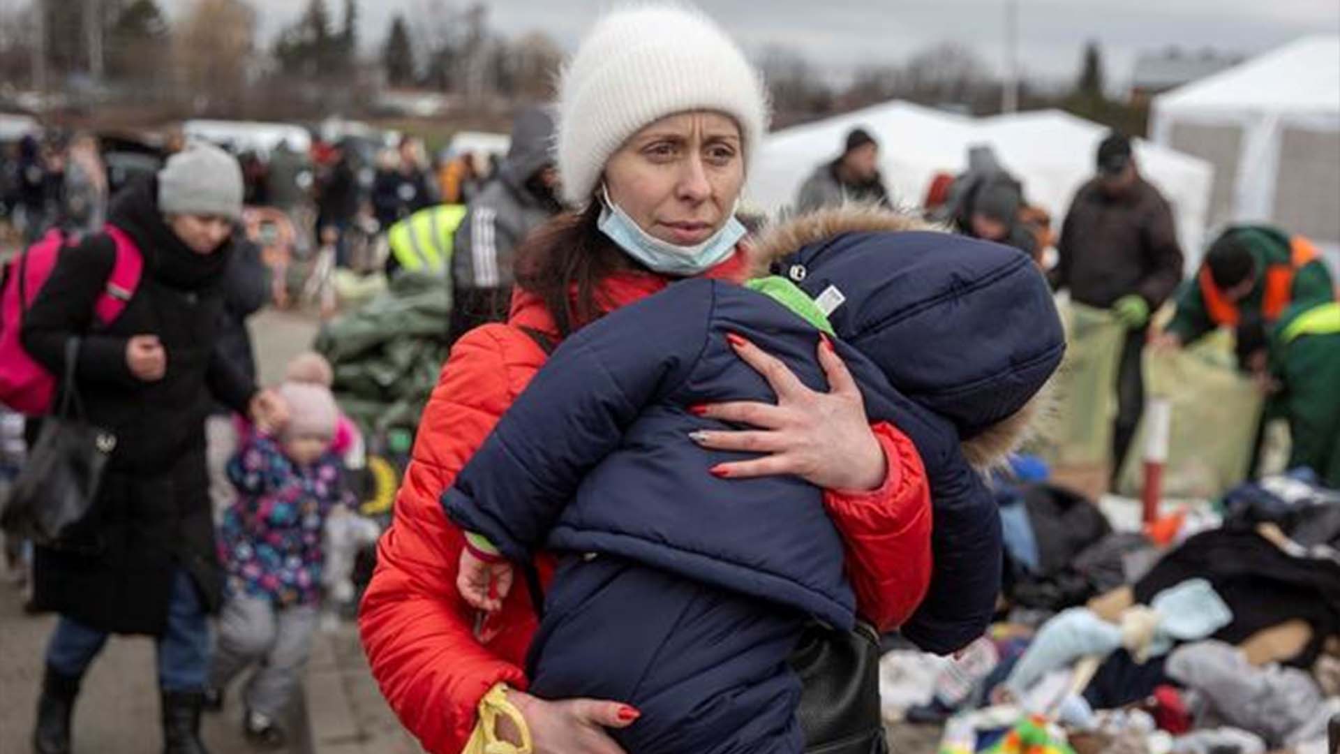Une femme porte son enfant alors qu'elle arrive au poste frontière de Medyka après avoir fui l'Ukraine, en Pologne, le lundi 28 février 2022.