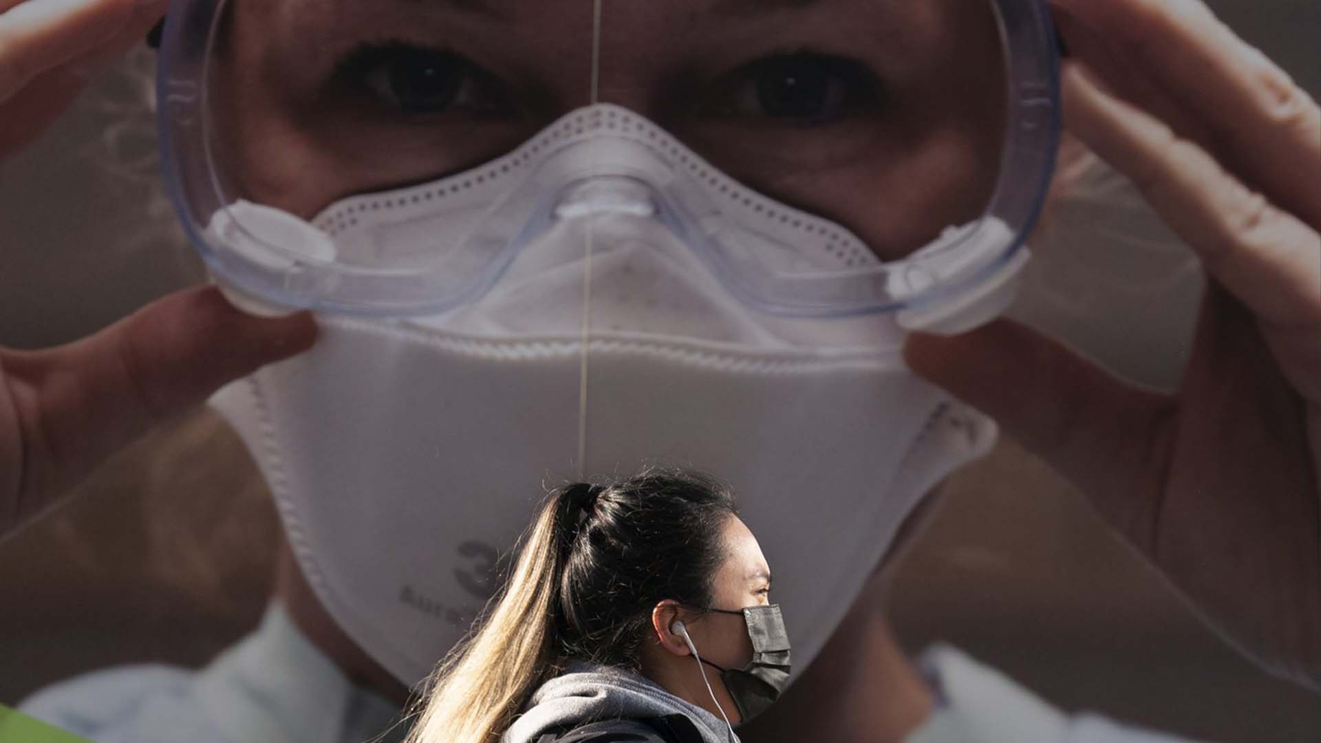Une femme porte un masque protecteur pour aider à prévenir la propagation du COVID-19 alors qu'elle passe devant un panneau d'affichage de l'hôpital général de Vancouver à Vancouver le jeudi 8 avril 2021.