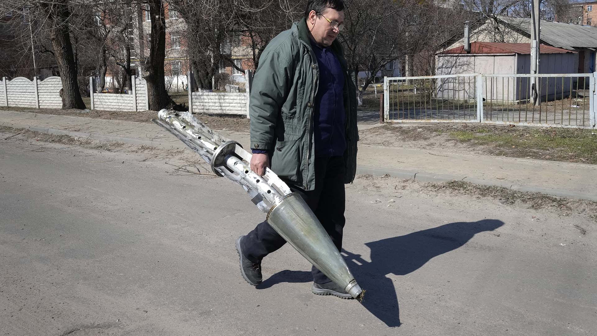 Un homme transporte un fragment d'une roquette russe à la suite de l'attaque à Kharkiv, en Ukraine, le vendredi 25 mars 2022.