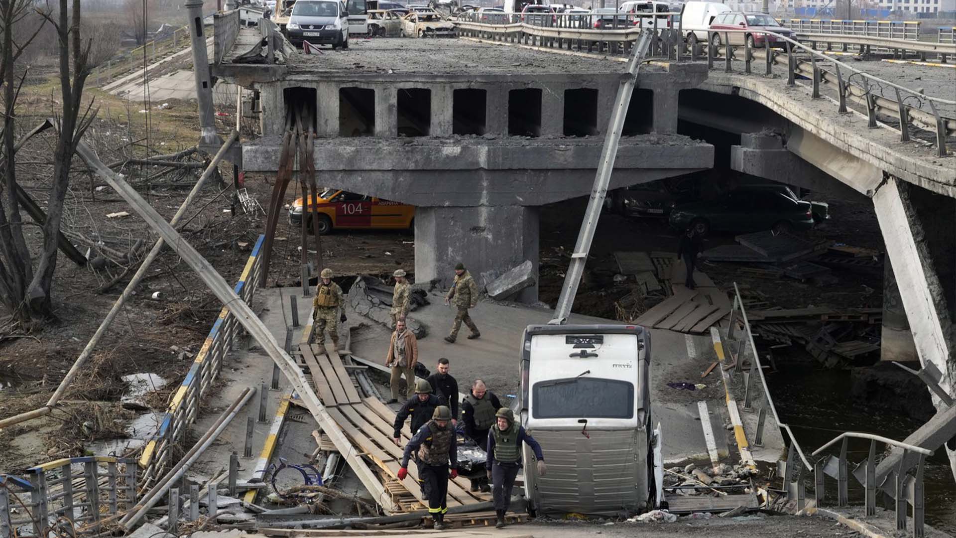 Des soldats ukrainiens transportent le corps d'un civil tué par les forces russes sur le pont détruit à Irpin près de Kiev, en Ukraine, le jeudi 31 mars 2022.