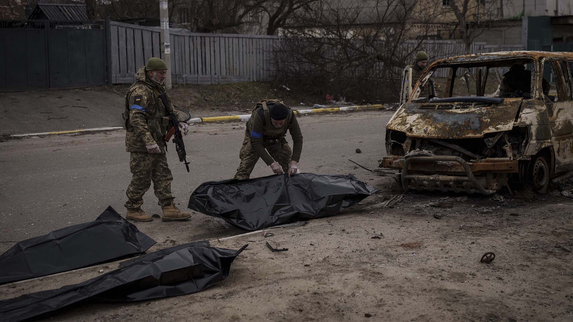 Des soldats ukrainiens récupèrent les restes de quatre civils tués à l'intérieur d'un véhicule calciné à Bucha, à la périphérie de Kiev, en Ukraine