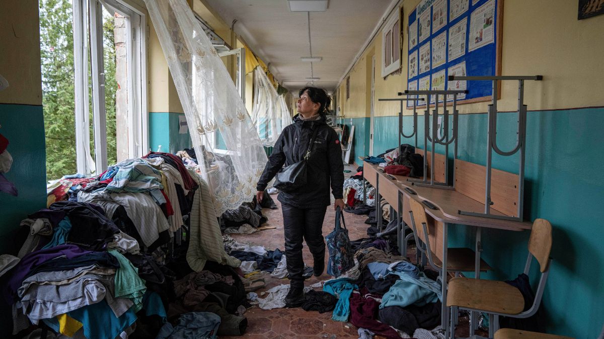 La directrice d'une école marche à travers les débris d'une autre institution qui a été victime des bombardements russes plus tôt dans le conflit.