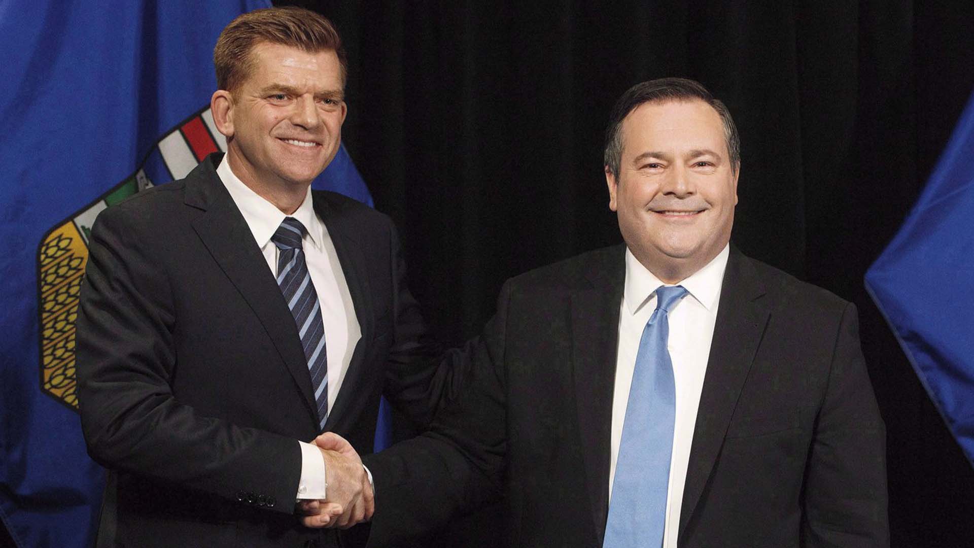 Le chef de l'Alberta Wildrose, Brian Jean, et le chef du PC de l'Alberta, Jason Kenney, se serrent la main après avoir annoncé un accord d'unité entre les deux partis à Edmonton le 18 mai 2017.
