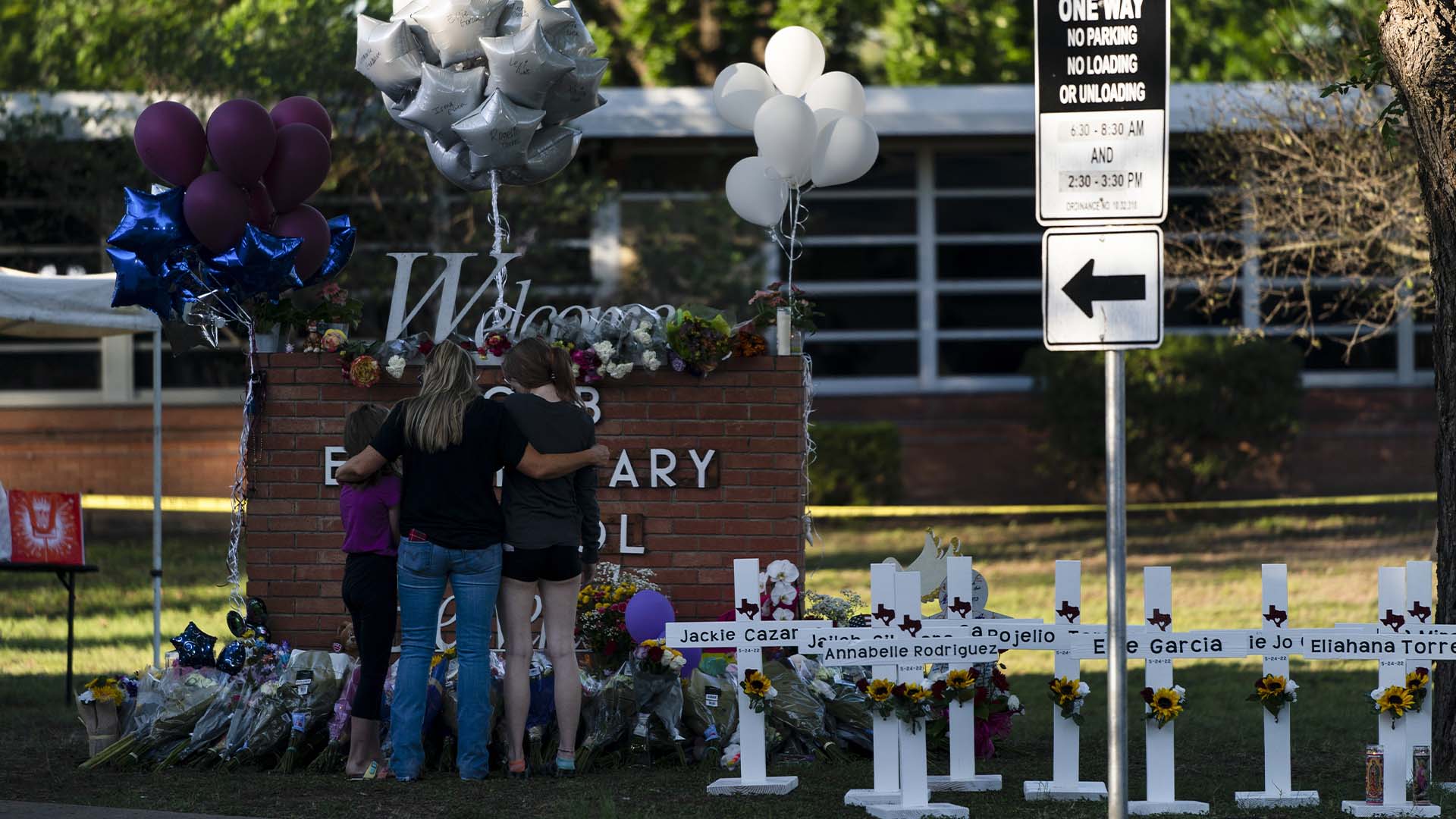 Sur cette image: Une famille rend hommage à côté des croix portant les noms des victimes de la fusillade. 