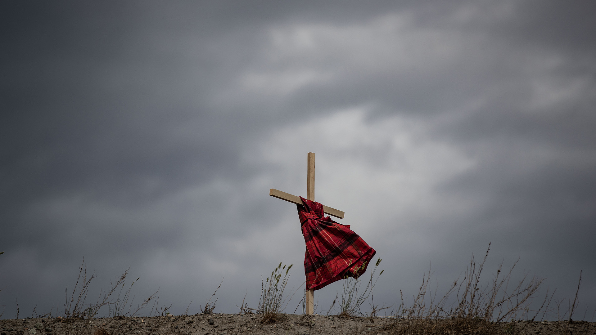 Une robe d'enfant accrochée à une croix souffle au vent près de l'ancien pensionnat indien de Kamloops, en l'honneur des 215 enfants dont les restes ont été découverts enterrés près de l'établissement, à Kamloops, en Colombie-Britannique, le vendredi 4 juin 2021.