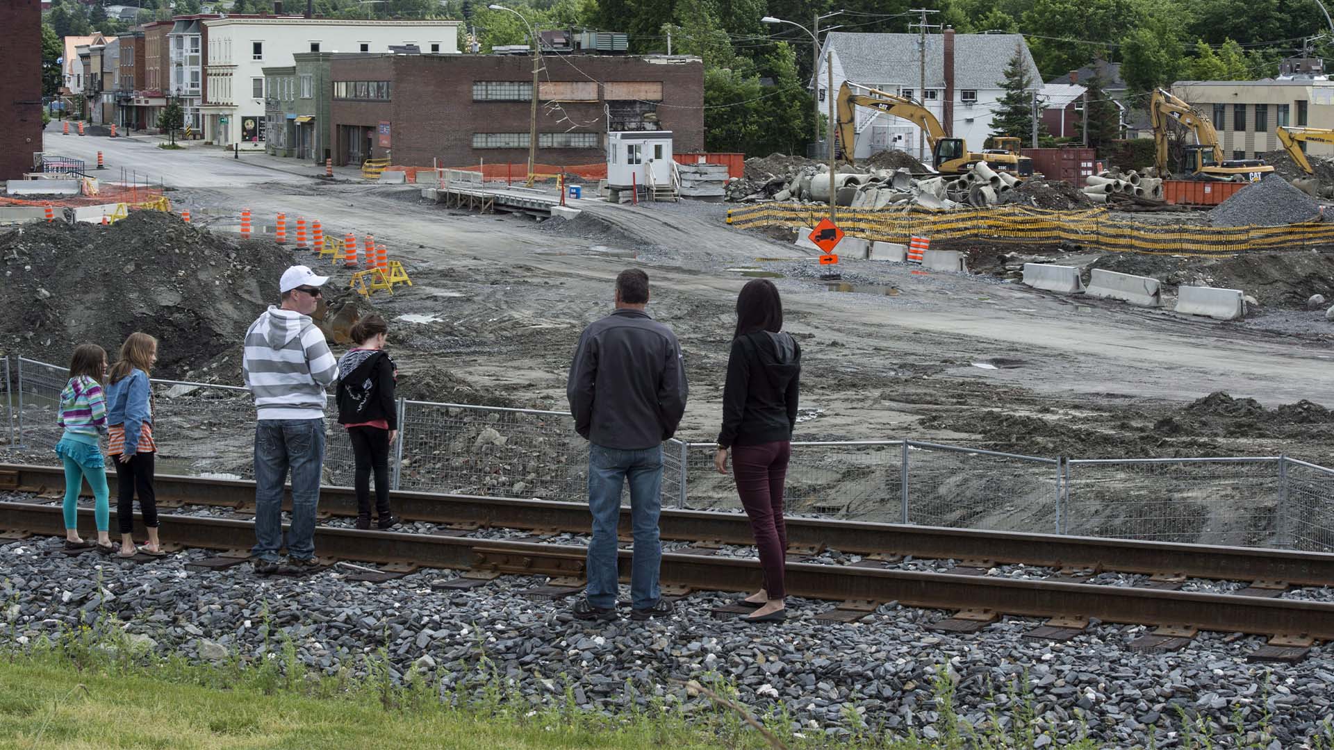 Des résidents se tiennent sur la voie ferrée à côté du site du déraillement de train de l'an dernier le samedi 5 juillet 2014 à Lac-Mégantic, au Québec. Il y a un an, un train rempli d'huile est sorti des rails et a explosé, tuant 47 personnes et détruisant une partie du centre-ville. 