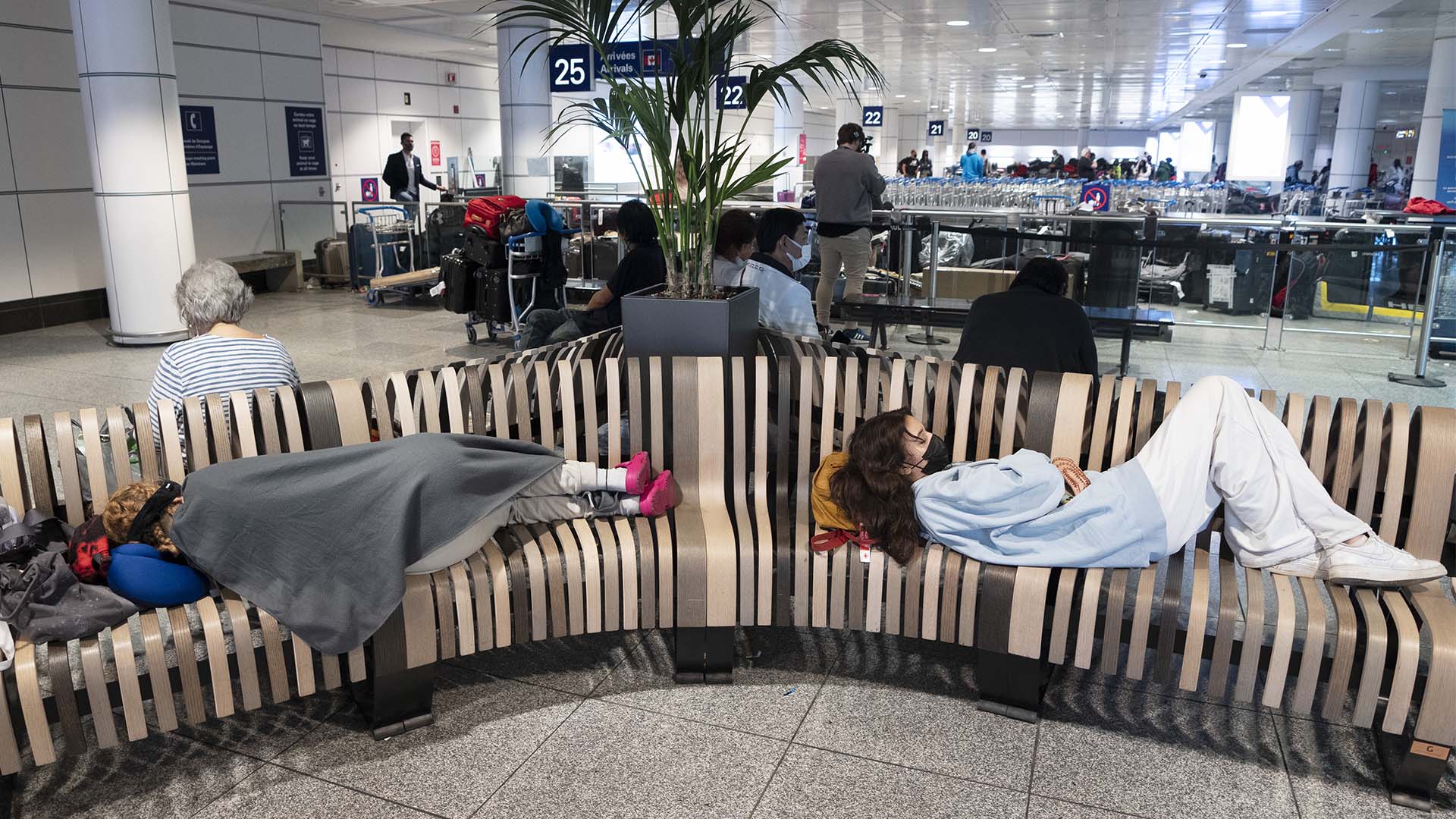 Des gens dorment sur un banc en attendant à l'aéroport Pierre Elliott Trudeau, à Montréal, le mercredi 29 juin 2022