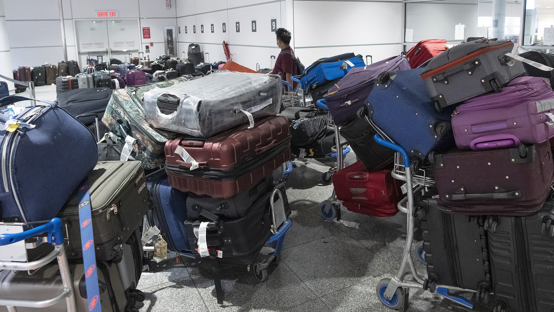 Un passager cherche ses bagages parmi une pile de bagages non réclamés à l'aéroport Pierre Elliott Trudeau, à Montréal, le mercredi 29 juin 2022.
