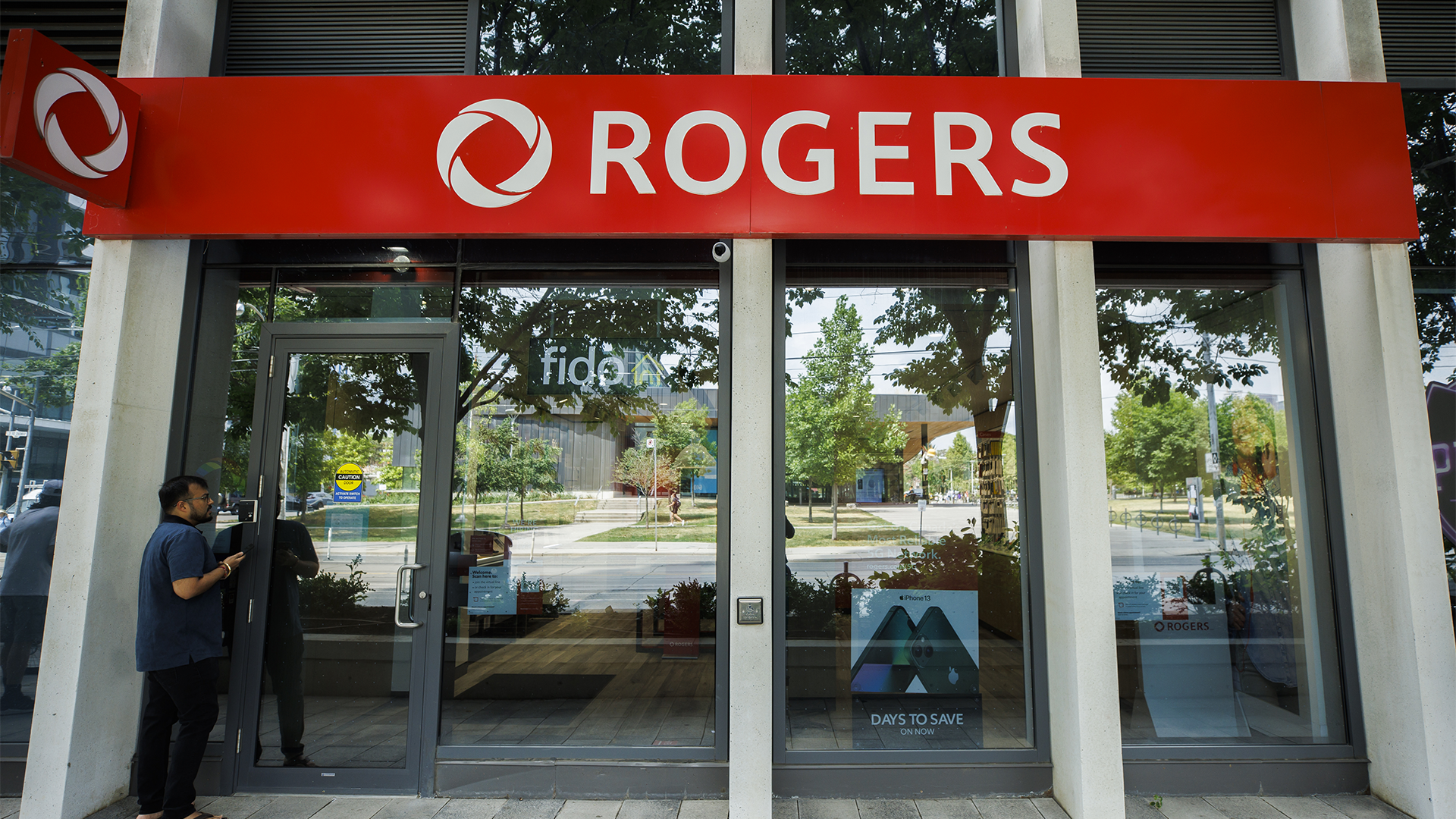 Un homme tente d'entrer dans une succursale Rogers de Toronto lors de la panne du 8 juillet.