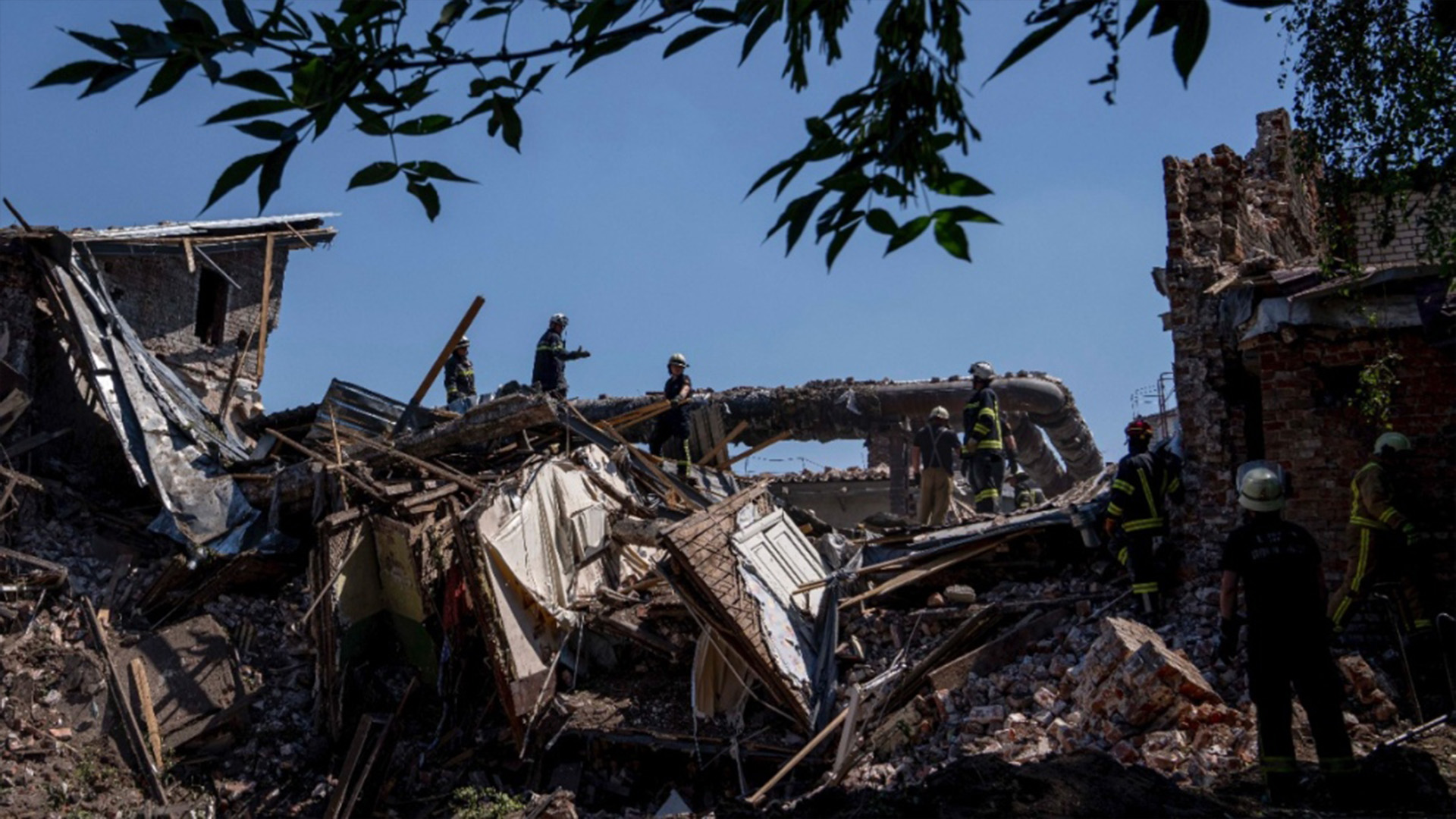 Des secouristes se tiennent sur les décombres sur les lieux après une frappe de missile dans un immeuble résidentiel à Chasiv Yar, dans la région de Donetsk, dans l'est de l'Ukraine, le 10 juillet 2022.