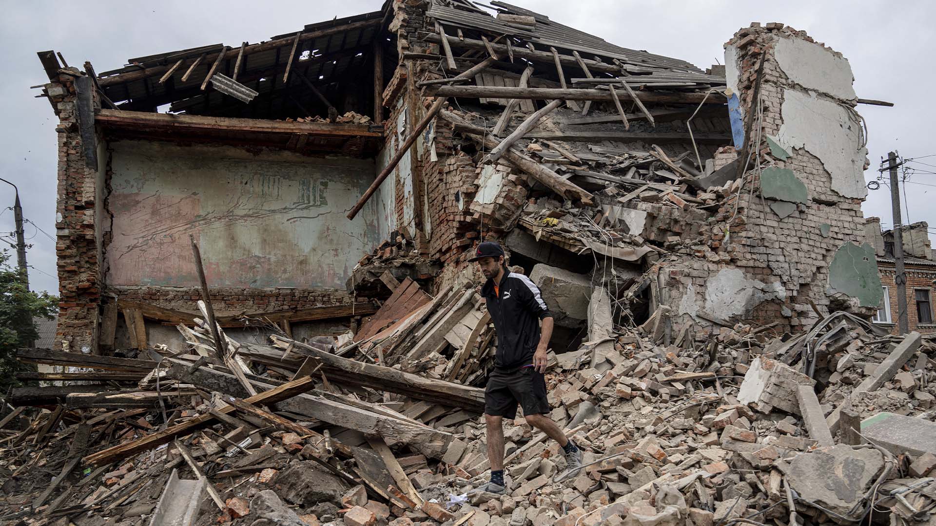 Un homme cherche les documents de son ami blessé dans les débris d'un immeuble détruit après un bombardement russe dans un quartier résidentiel de Chuhuiv.
