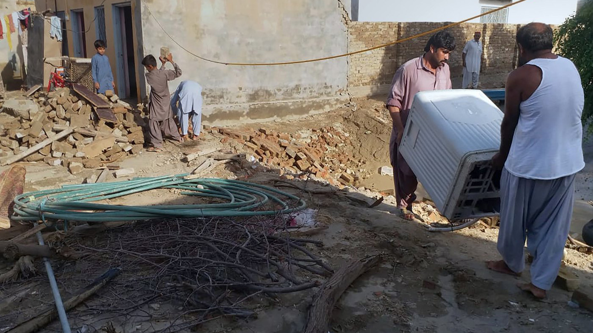 Des habitants récupèrent des objets utilisables de leur maison, qui s'est partiellement effondrée en raison de fortes pluies, à Taunsa Sharif, dans le centre du Pakistan, le lundi 22 août 2022.