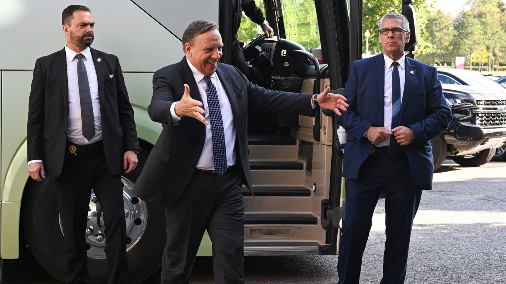 Le chef de la Coalition Avenir Québec, François Legault, est entouré de gardes du corps alors qu'il fait un geste vers un candidat, près de son autobus de campagne, le mardi 6 septembre 2022 à Bécancour, au Québec.