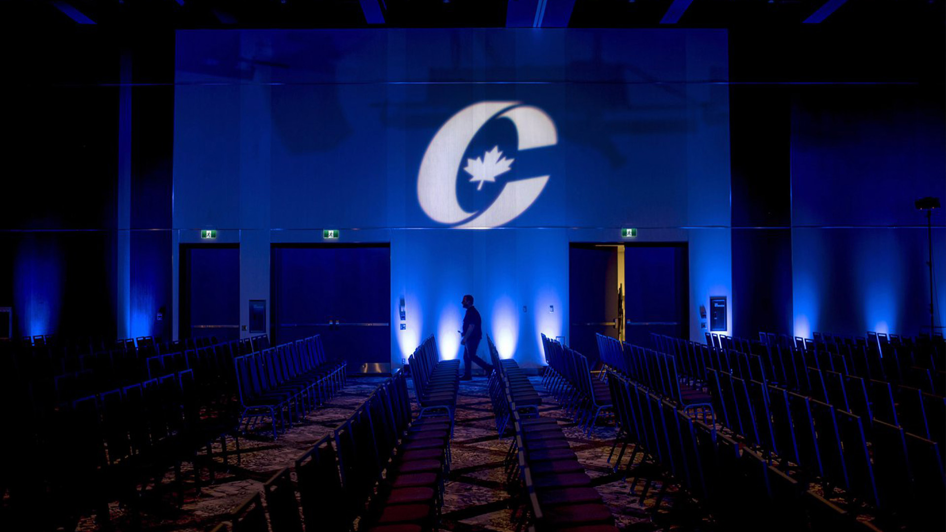 La silhouette d'un homme passe devant un logo du Parti conservateur avant l'ouverture du congrès national du Parti à Halifax le jeudi 23 août 2018.
