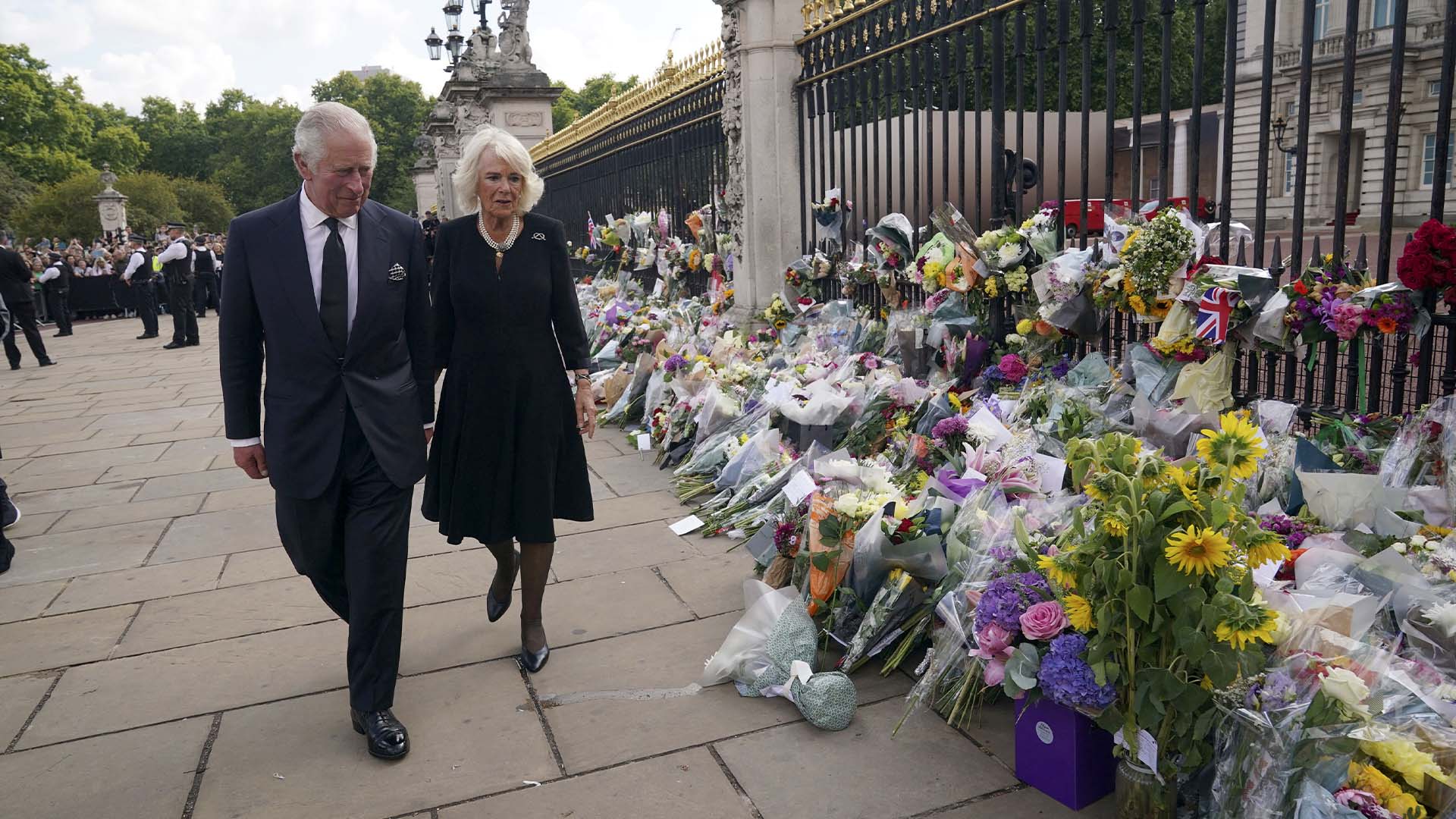 Le roi Charles III, à gauche, et Camilla, la reine consort, passent devant des hommages floraux laissés devant le palais de Buckingham après la mort jeudi de la reine Elizabeth II, à Londres, le vendredi 9 septembre