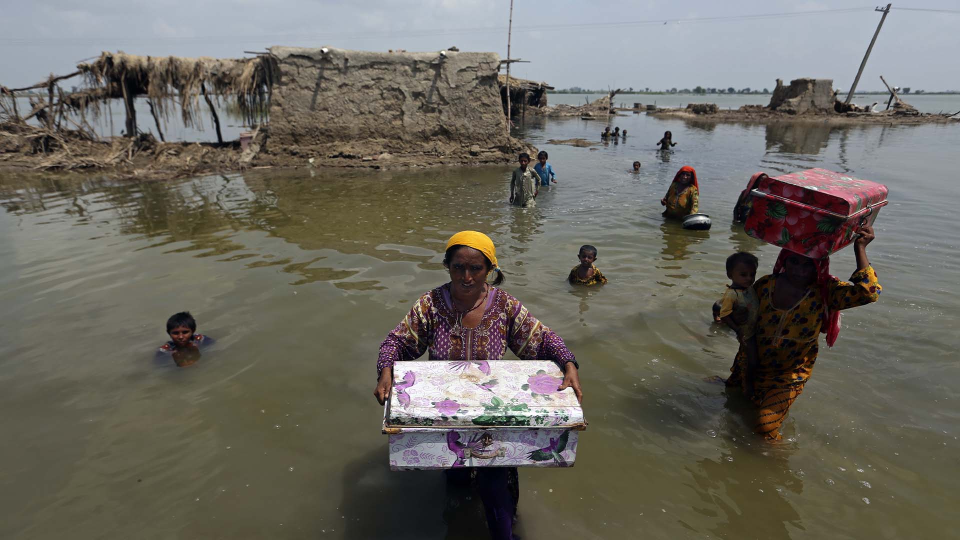 Des femmes transportent des biens sauvés de leur maison inondée après les pluies de mousson, dans le district de Qambar Shahdadkot de la province de Sindh, au Pakistan, le 6 septembre 2022. 