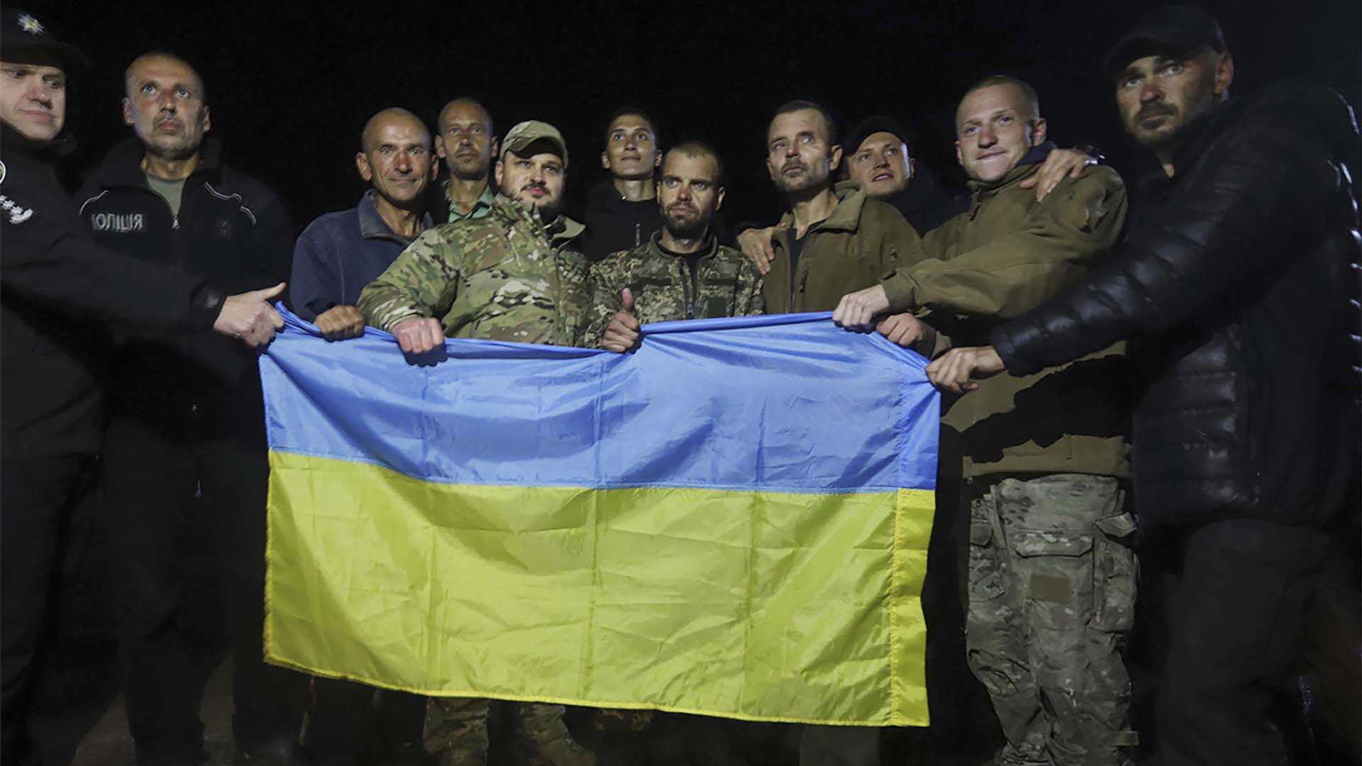 Sur cette photo fournie par le bureau de presse du service de sécurité ukrainien, des soldats ukrainiens libérés lors d'un échange de prisonniers entre la Russie et l'Ukraine tiennent le drapeau ukrainien près de Tchernihiv, en Ukraine, mercredi 21 septembre 2022.