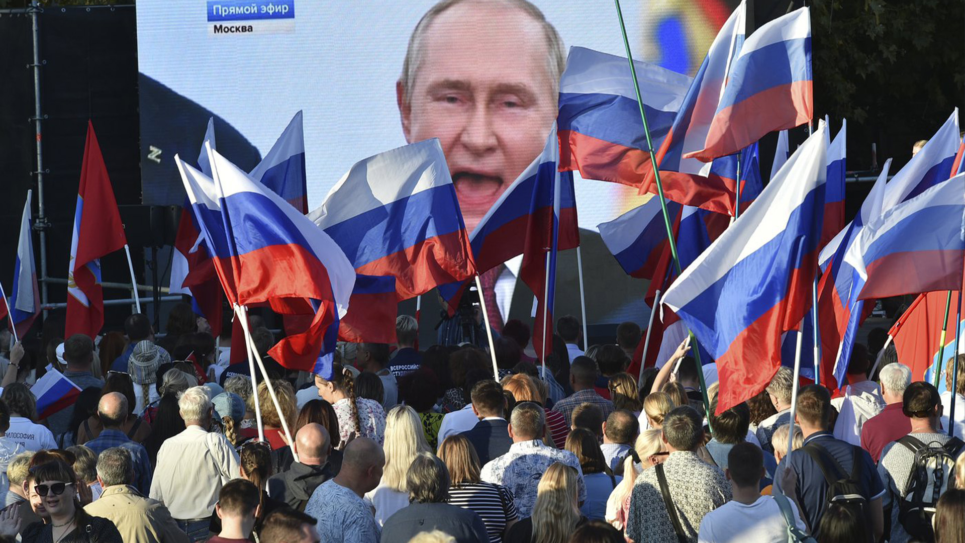 Les gens regardent le président russe Vladimir Poutine prononcer son discours après une cérémonie de signature des traités pour que quatre régions d'Ukraine rejoignent la Russie au Kremlin de Moscou, lors d'une réunion à Sébastopol, en Crimée, le vendredi 30 septembre 2022.