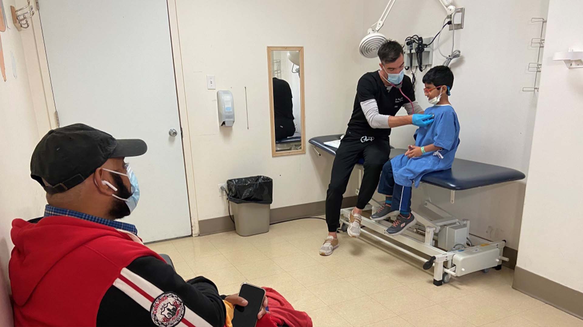 Azhar Chaudhry observe le Dr Hugo Paquin qui examine son fils Abdureeh à l'hôpital Sainte-Justine.