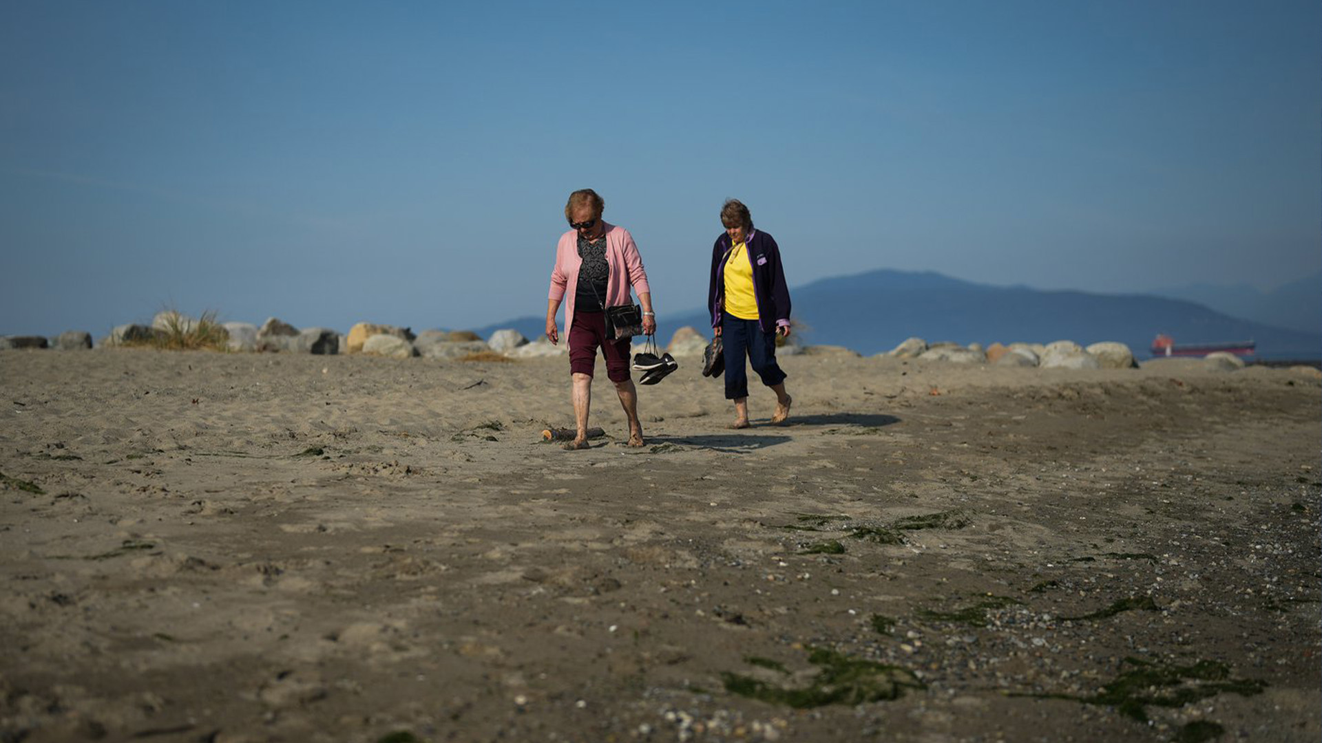 Deux femmes portent leurs chaussures alors qu'elles marchent ensemble à Spanish Banks Beach pendant une période de temps inhabituellement chaud à Vancouver, en Colombie-Britannique, le jeudi 6 octobre 2022.