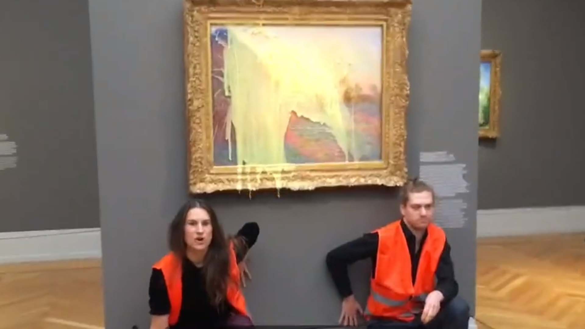 Les militants, tous deux vêtus de gilets orange à haute visibilité, se sont également collés au mur sous le tableau.
