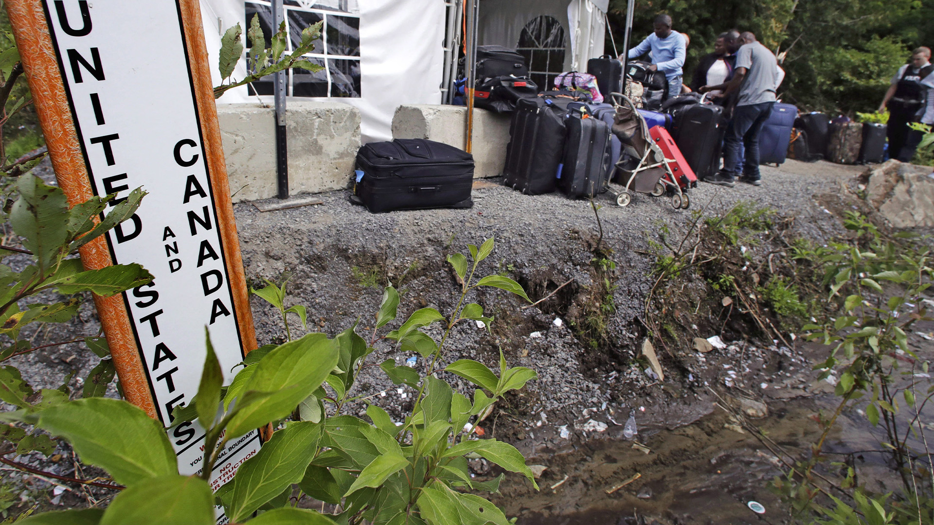 Dans cette photo d'archive du 7 août 2017, des migrants empilent leurs bagages devant un poste de police de fortune après être entrés illégalement au Canada au bout de Roxham Road à Champlain, N.Y., alors qu'ils se dirigeaient vers un poste frontière non officiel en face de Saint-Bernard-de -Lacolle, Québec.