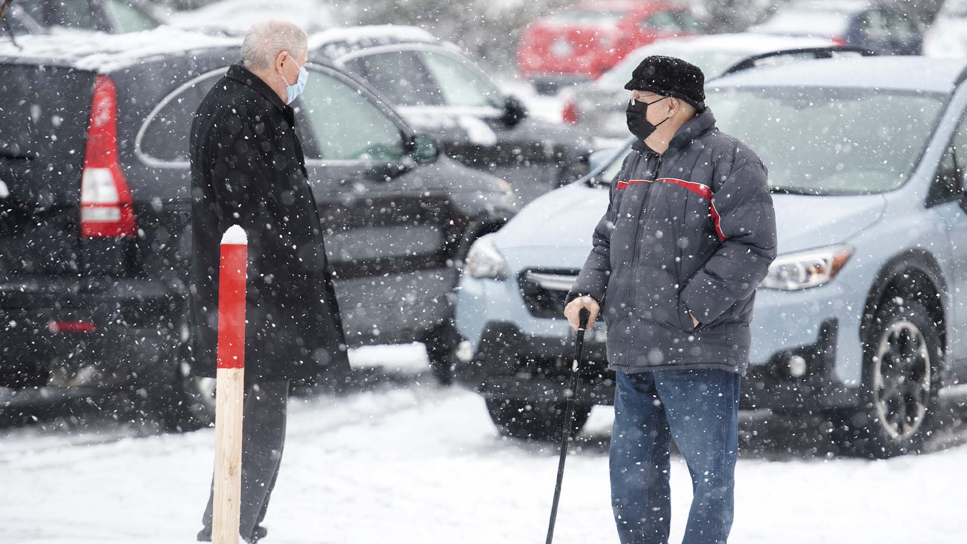 Des personnes portent des masques lors d'une chute de neige à Montréal, le 16 novembre 2022. 
