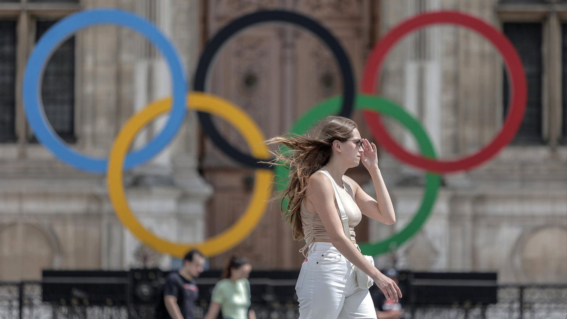 Une femme passe devant les anneaux olympiques à l'hôtel de ville de Paris, le 25 juillet 2022. La Lettonie menace de boycotter les Jeux olympiques de Paris l'année prochaine si les athlètes de Russie et de son allié biélorusse sont autorisés à participer après l'invasion de l'Ukraine par la Russie.
