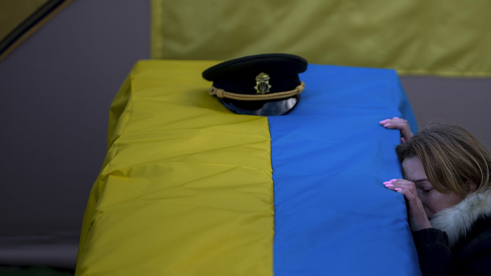 Une femme s'agenouille près du cercueil de son mari, un combattant ukrainien mort au combat.
