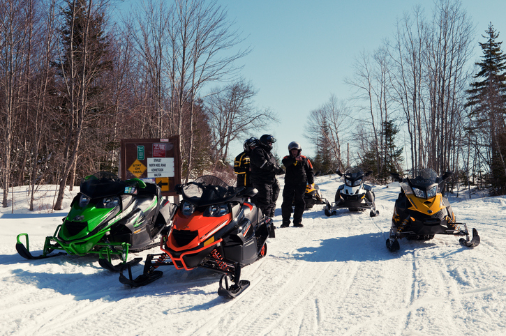 Kennetcook, Nova Scotia, Canada - February 24, 2011: Snowmobilers stop for a break from the trails to stretch their legs and check their planned route.