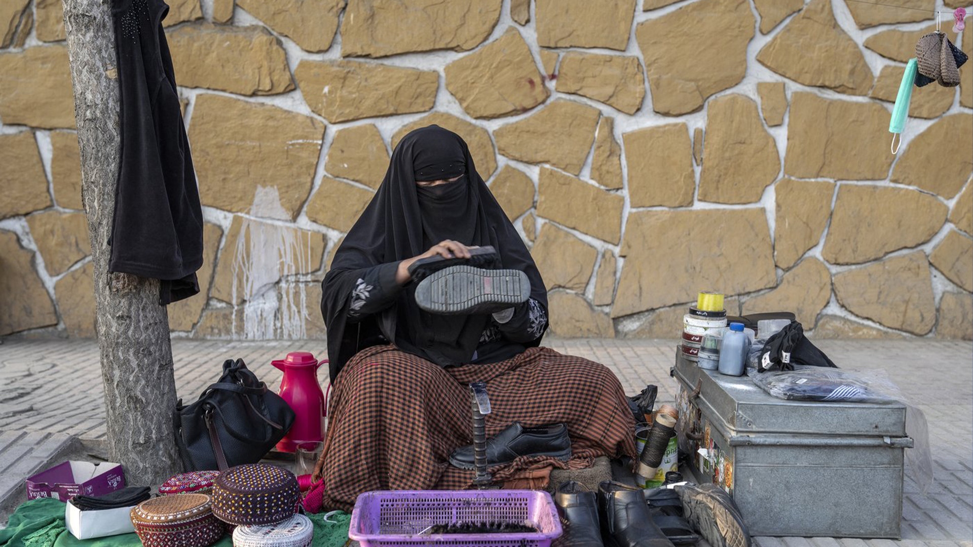 Une femme afghane nettoie les chaussures des clients dans une rue de Kaboul, en Afghanistan, le dimanche 5 mars 2023. Après l'arrivée au pouvoir des talibans en Afghanistan, les femmes ont été privées de bon nombre de leurs droits fondamentaux.