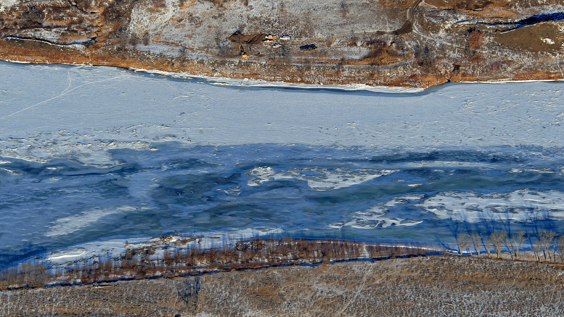 ARCHIVE - Des équipes de nettoyage travaillent pour contenir une fuite de pétrole provenant du pipeline endommagé de Bridger Pipeline près de Glendive, dans le Montana, le 19 janvier 2015, dans cette vue aérienne montrant les deux côtés de la rivière. 