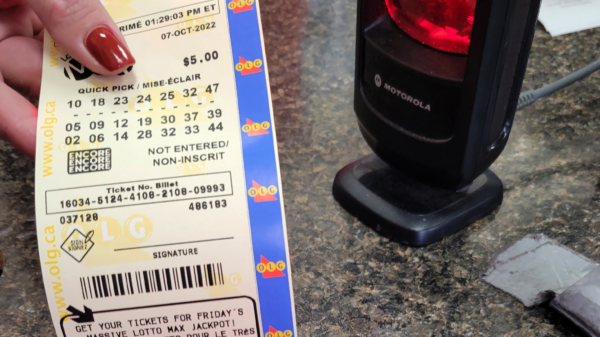 Un préposé remet à un client son billet Lotto Max dans une station-service au nord de Newcastle, en Ontario, le jeudi 6 octobre 2022.