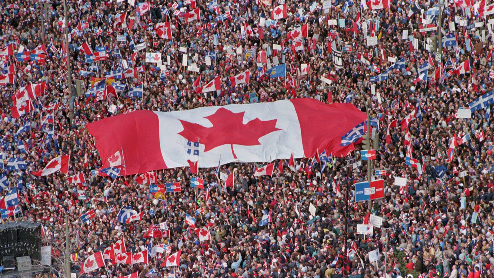 Un grand drapeau canadien traverse une foule dans cette photo d'archive du vendredi 27 octobre 1995, alors que des milliers de personnes affluaient à Montréal de partout au Canada pour se joindre aux Québécois qui se rassemblaient pour l'unité nationale trois jours avant un référendum qui pourrait pousser le Québec vers la sécession. Dimanche marque le 10e anniversaire du référendum sur la souveraineté du Québec tenu le 30 octobre 1995.