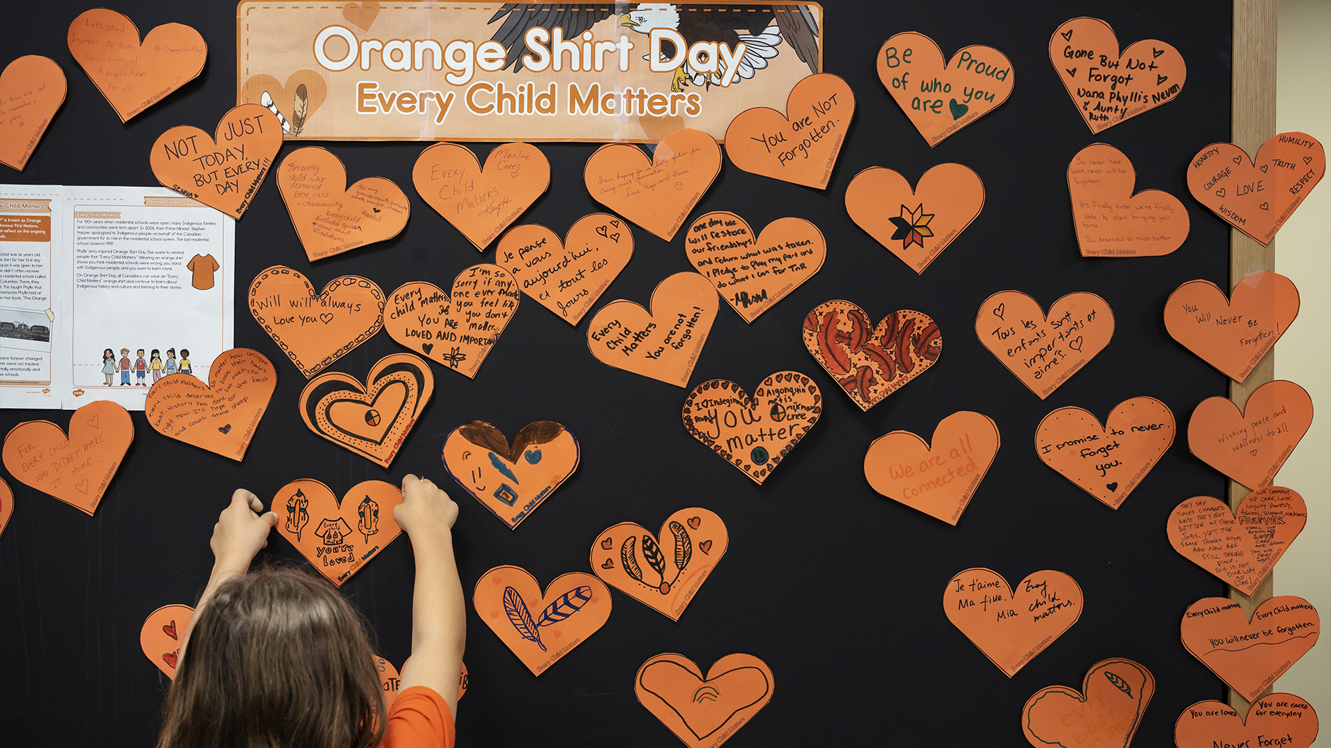 Une enfant place un cœur orange qu'elle a décoré lors d'une activité artistique et historique marquant la Journée nationale de la Vérité et de la Réconciliation au Centre d'amitié autochtone Mi'kmaw à Halifax le samedi 30 septembre 2023.