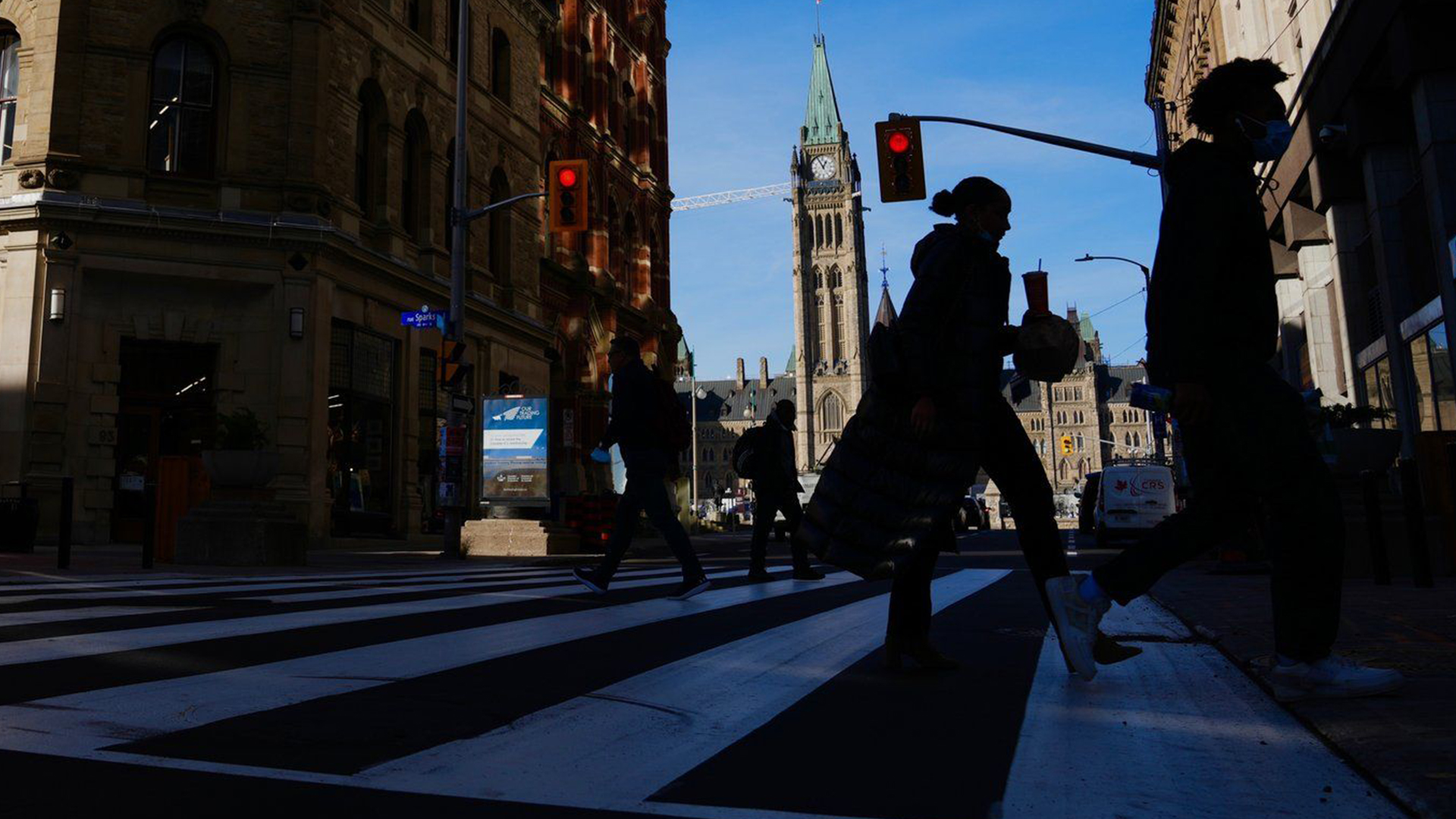 Le drapeau canadien flotte sur la Colline du Parlement alors que les piétons se dirigent vers le centre commercial de la rue Sparks à Ottawa, le mardi 9 novembre 2021.