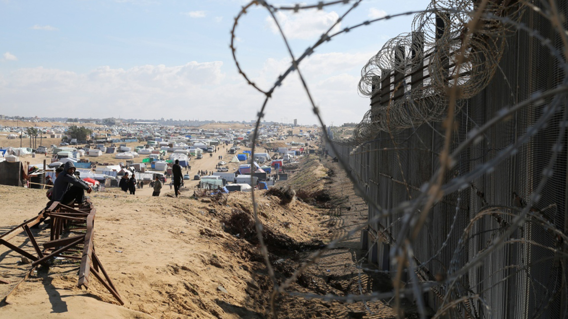 Des Palestiniens déplacés par l'offensive aérienne et terrestre d'Israël sur la bande de Gaza sont assis à côté de la barrière frontalière avec l'Égypte à Rafah, mercredi 24 janvier 2024. 
