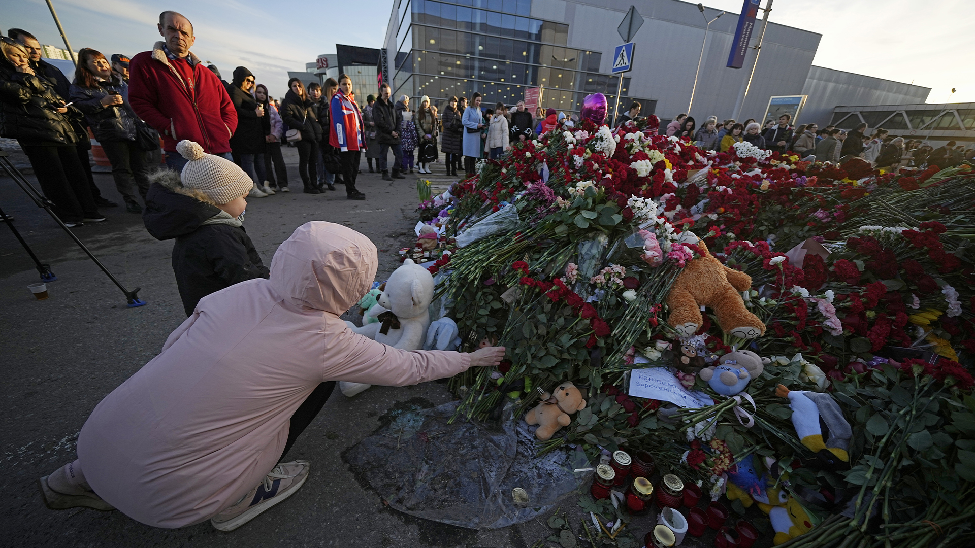 Des personnes déposent des fleurs sur un mémorial improvisé devant l'hôtel de ville de Crocus en Russie, le 25 mars 2024.