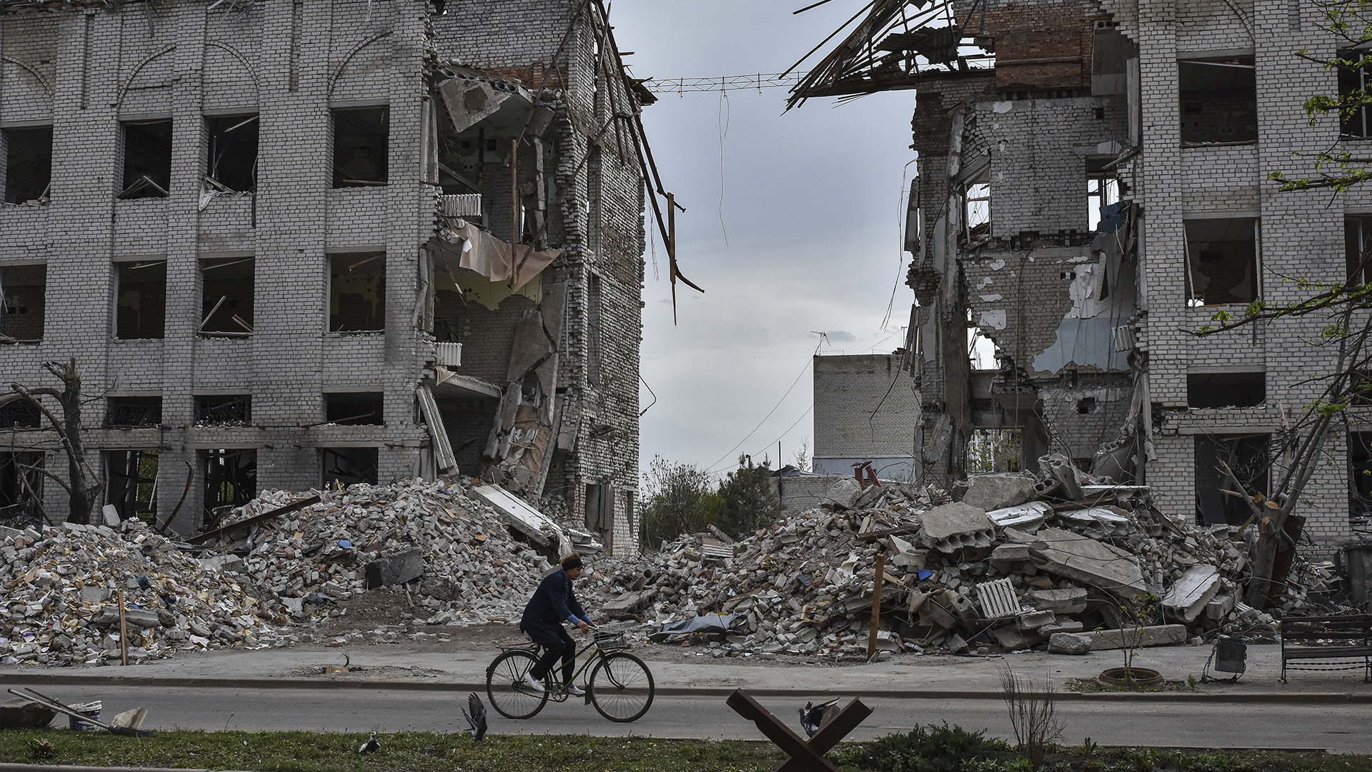 Une femme fait du vélo devant un bâtiment détruit par une frappe aérienne russe dans la ville d'Orikhiv, sur la ligne de front, en Ukraine, le jeudi 18 avril 2024. 