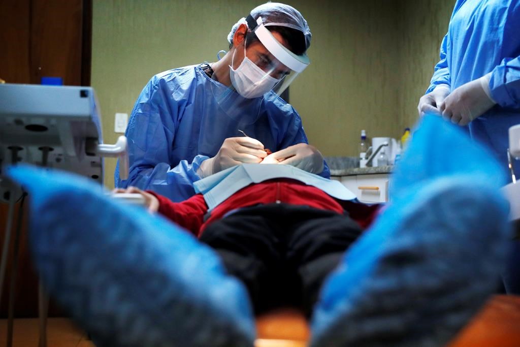 A dentist attends to a child at a family clinic in Asuncion, Paraguay, Tuesday, June 2, 2020. Health department officials say the federal government plans to hire a third-party company to process claims for its new dental-care insurance program. THE CANADIAN PRESS/AP, Jorge Saenz