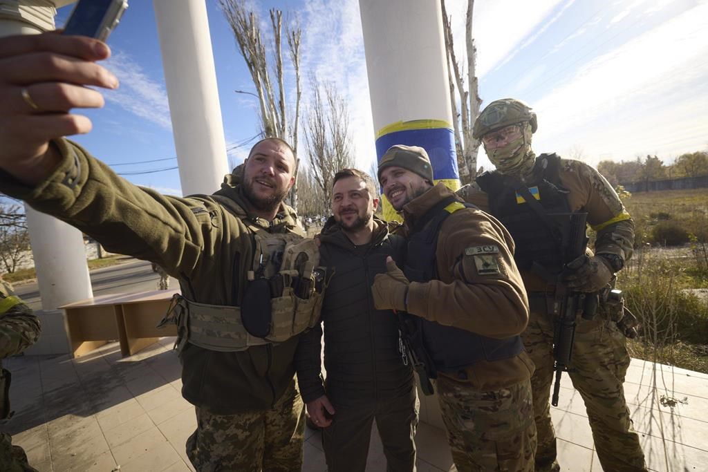 Sur cette photo fournie par le Bureau de presse présidentiel ukrainien et publiée sur Facebook, des soldats ukrainiens prennent un selfie avec le président Volodymyr Zelenskyy, au centre, lors de sa visite à Kherson, en Ukraine, le lundi 14 novembre 2022.