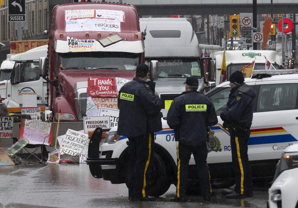 Police officers keep an eye on protest trucks in Ottawa, Thursday, Feb. 17, 2022. Day 24 of the Public Order Emergency Commission will hear from the former head of the Canada Border Services Agency and senior Transport Canada officials. THE CANADIAN PRESS/Adrian Wyld