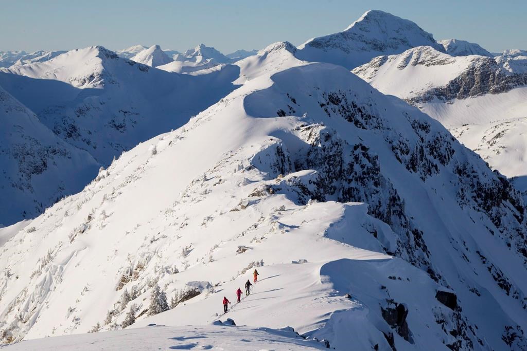 Backcountry skiers are dwarfed by the mountains as they make their way along a mountain ridge near McGillivray Pass Lodge located in the southern Chilcotin Mountains of British Columbia, Tuesday, Jan. 10, 2012. THE CANADIAN PRESS/Jonathan Hayward