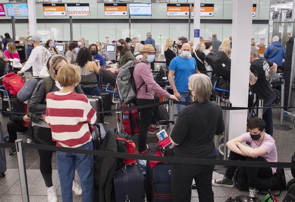 Travellers wait in line at a Sunwing Airlines check-in desk at Trudeau Airport in Montreal, Wednesday, April 20, 2022. THE CANADIAN PRESS/Graham Hughes